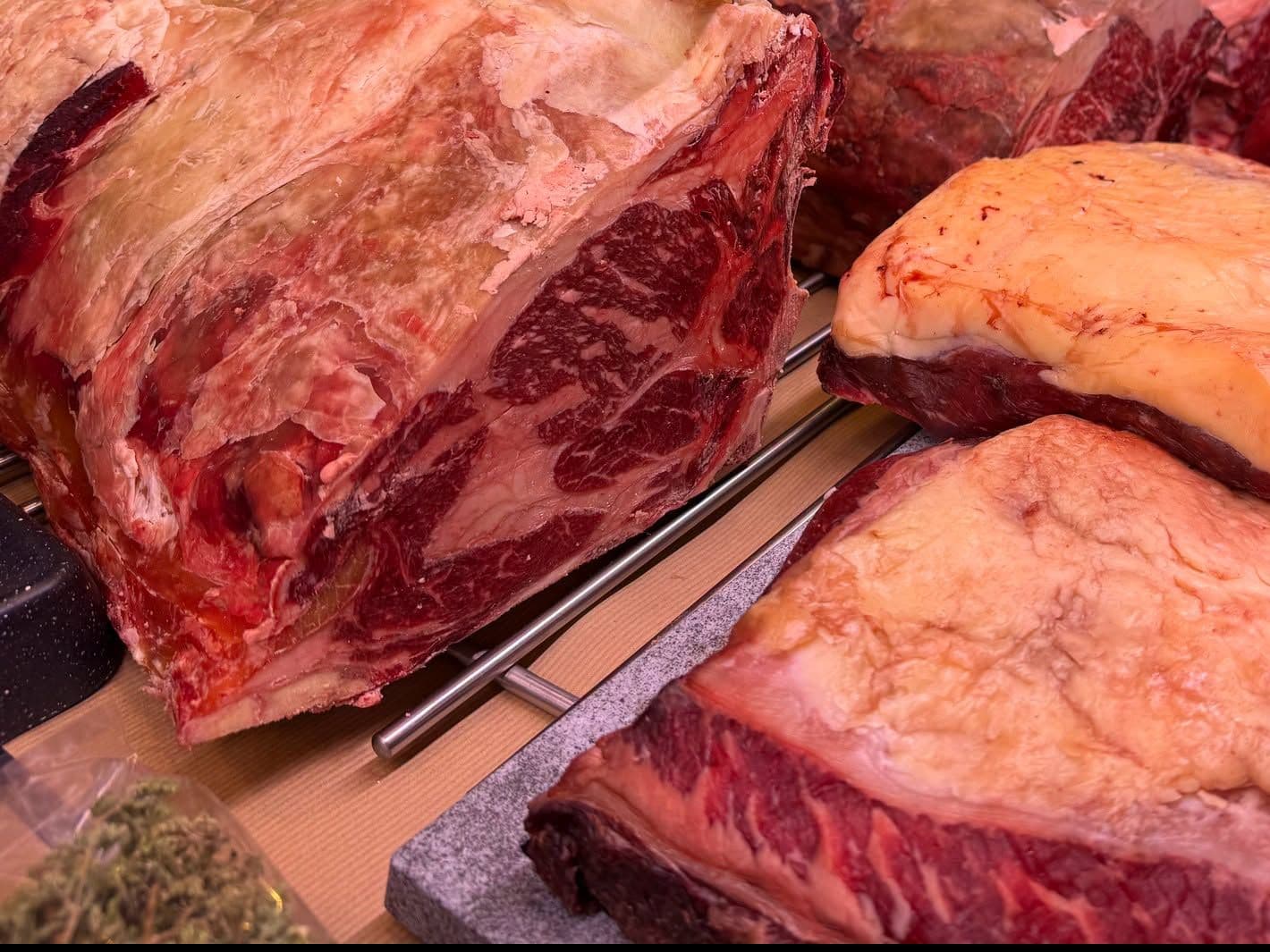 Des trains de côtes de bœuf maturés dans la vitrine, la chair rouge sombre et le gras jauni par la maturation