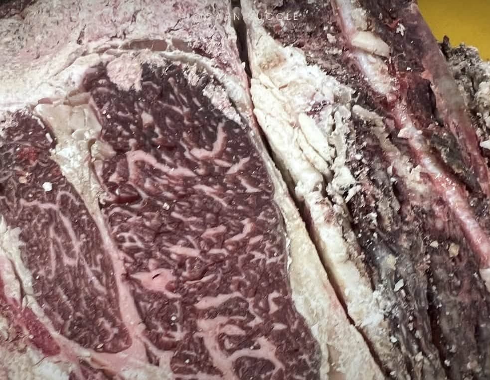 La tranche d'une pièce de bœuf maturé, la croûte sombre autour d'une chair très persillée