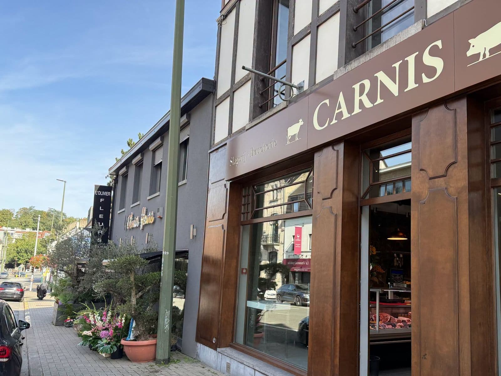 La devanture de Carnis chaussée de Waterloo : l'enseigne brune avec le nom en lettres claires, la vache et le cochon, les boiseries et la porte ouverte