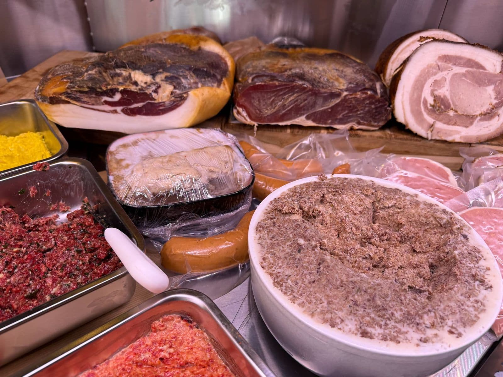 Des jambons secs, une poitrine roulée, un pâté en terrine et des préparations de viande dans la vitrine