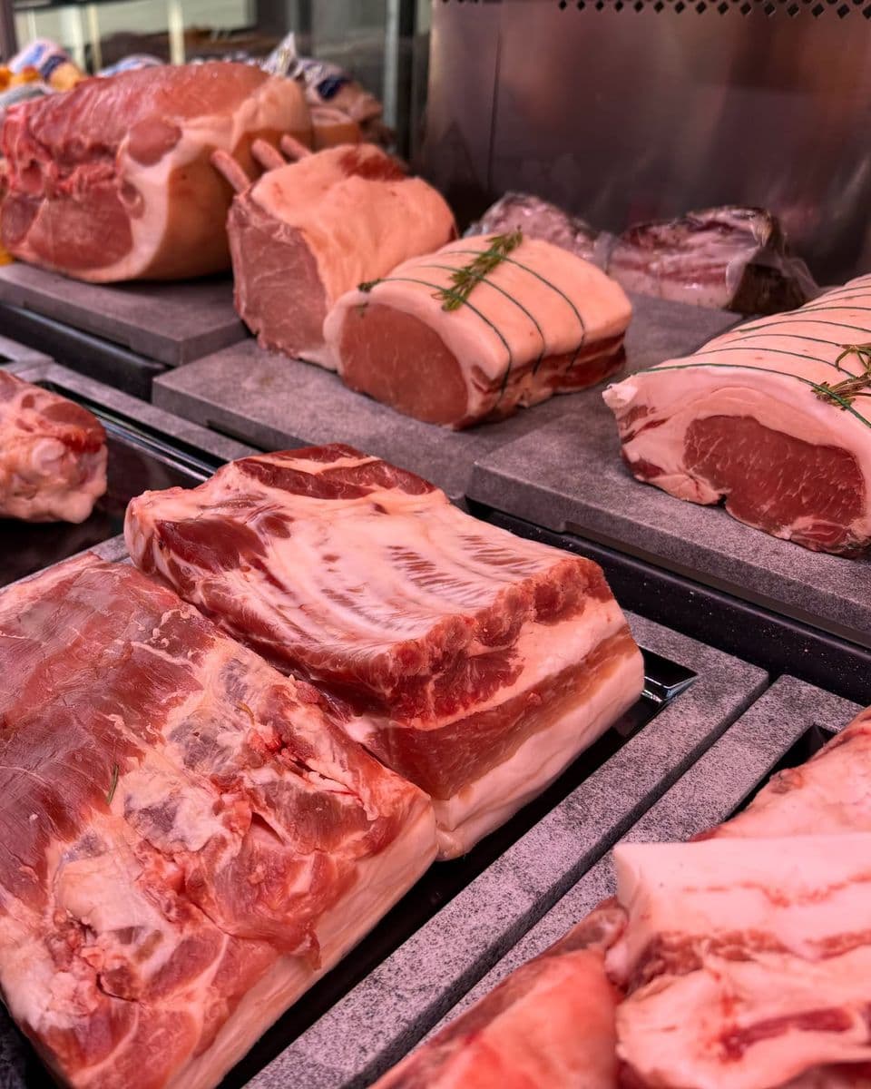 Des rôtis de porc ficelés au romarin et des pièces de porc entières sur les plateaux de pierre de la vitrine