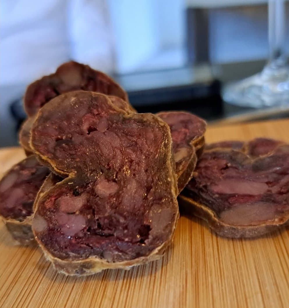 Des tranches épaisses de saucisson sec posées sur une planche en bois